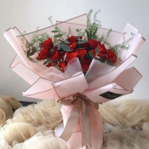 Букет 19 красных роз с зеленью и розовым оформлением